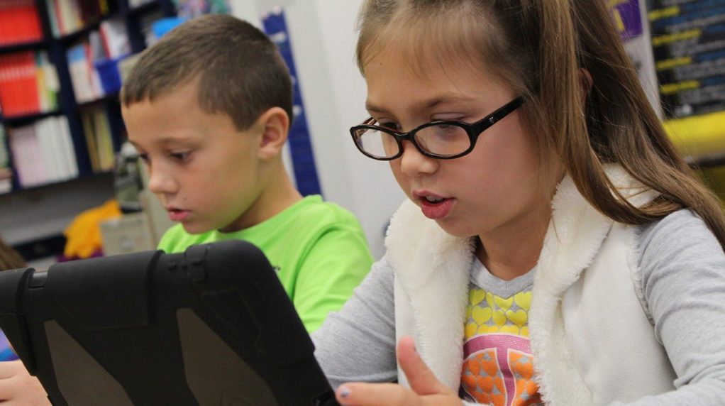 Two children using iPads in a classroom