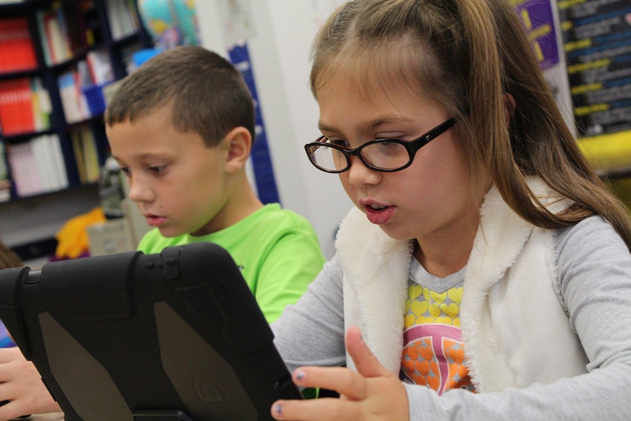 Two children using iPads in a classroom