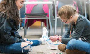 A general education student peer mentoring a Special Education student.