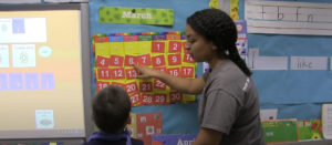 A teacher talking to a student in a classroom.