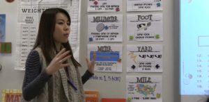 A teacher speaking in front of a classroom of students.