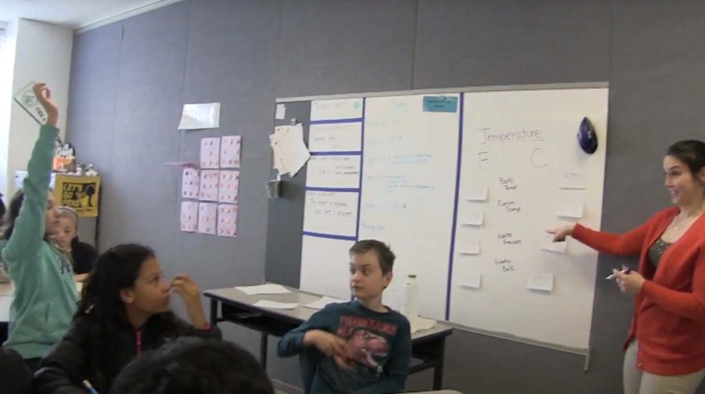A teacher speaking to a classroom full of students.