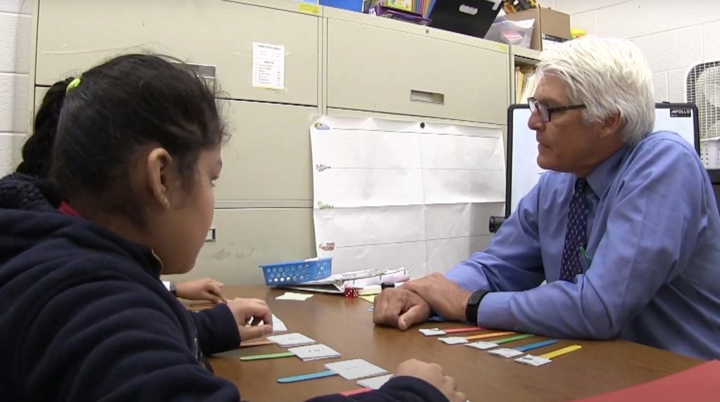 A teacher speaking with two students in his office.