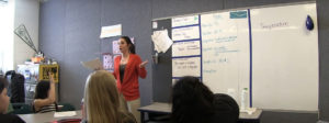 A teacher speaking to students in a classroom.