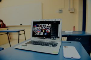 A laptop on a students desk showing a zoom meeting.